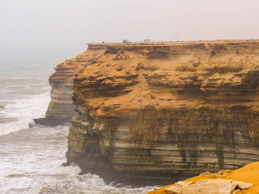 A weathered headland dropping into a hazy Atlantic swell