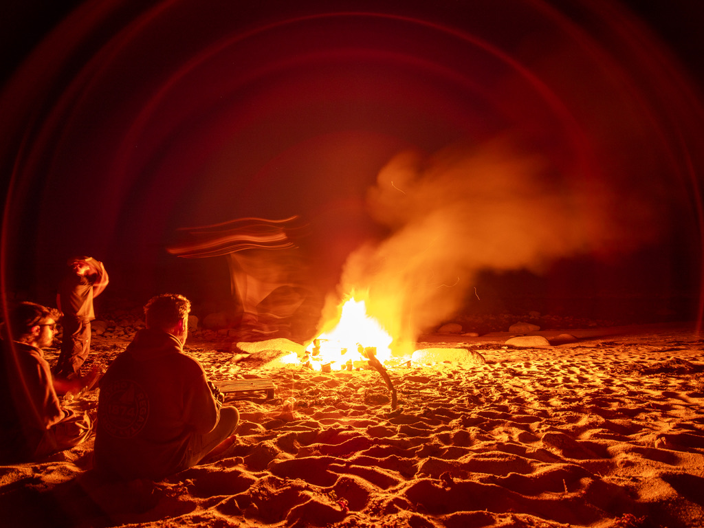 Friends gathered around a campfire on the beach at night