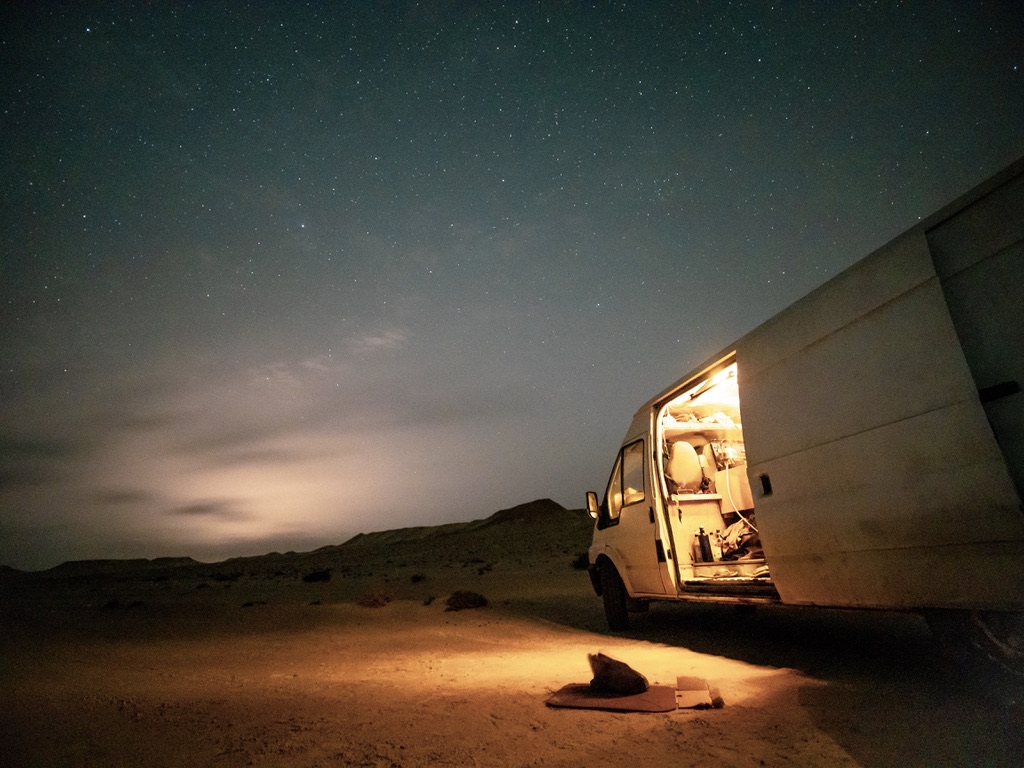 A camper van lit up under a star-filled desert sky