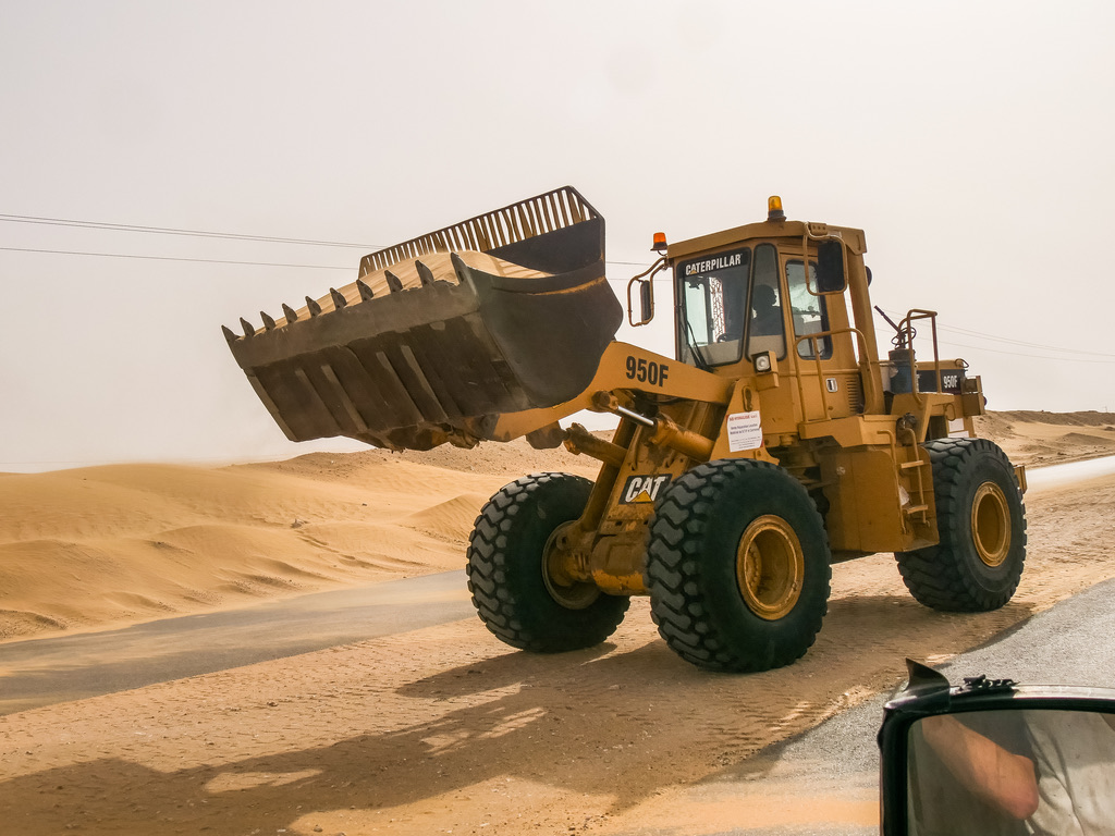A Caterpillar wheel loader working a sand-blown desert road