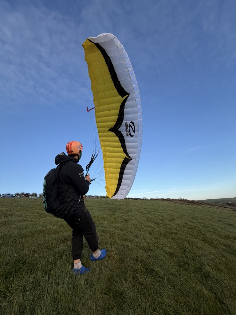 Flying a yellow kite on a green hilltop