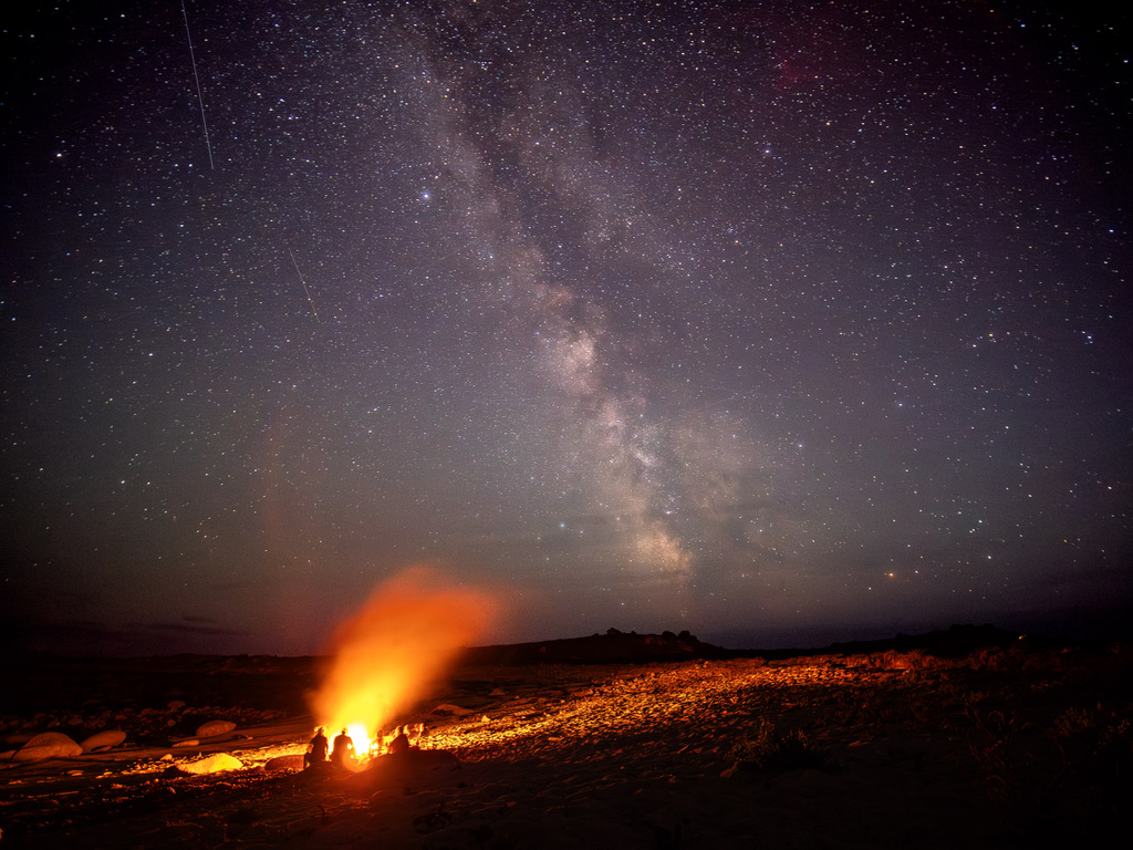 A glowing lava flow beneath a star-filled night sky