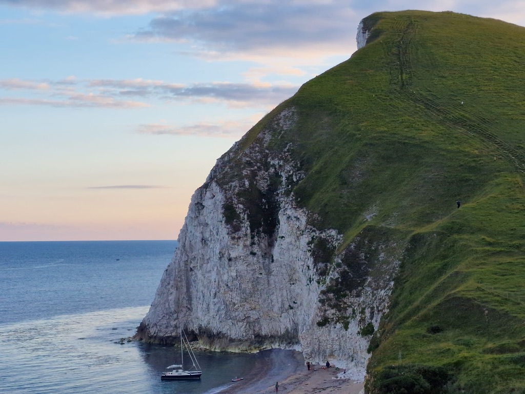 Steep green sea cliffs falling to the ocean in warm evening light
