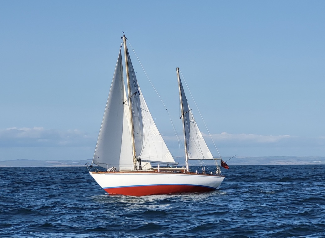 A classic ketch sailing under full canvas on open blue water