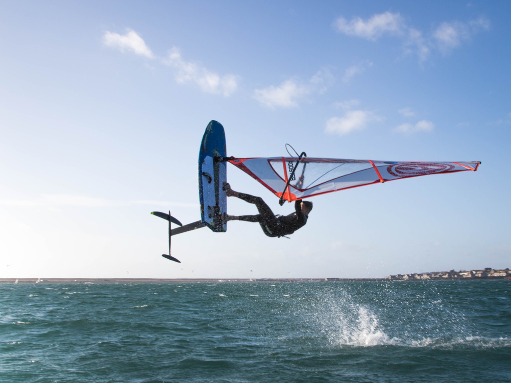 A windsurfer airborne on a hydrofoil board above choppy water