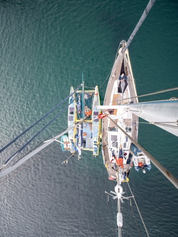 Overhead view looking straight down at a sailing yacht on dark water